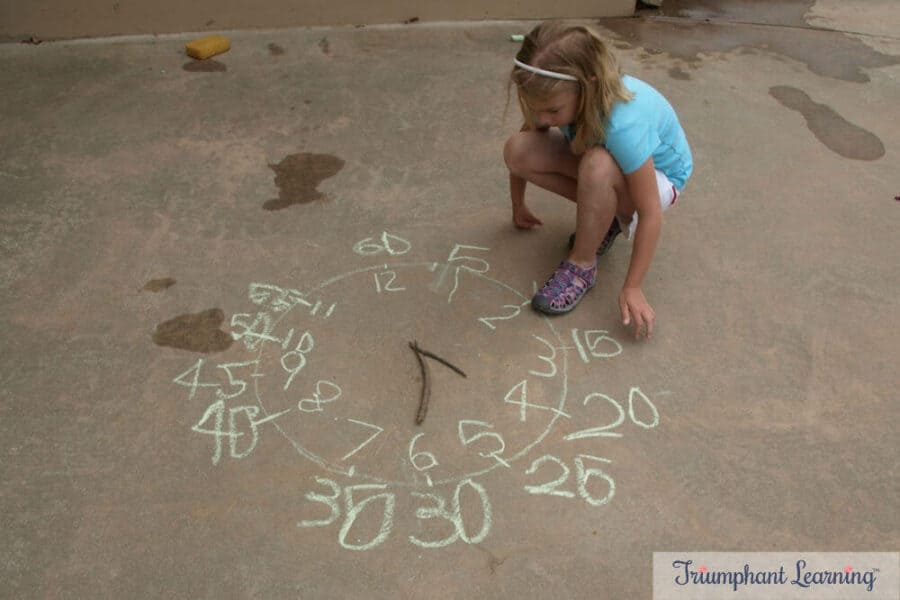 Drawing a clock and using sticks for the hands of the clock as she learns to tell time.